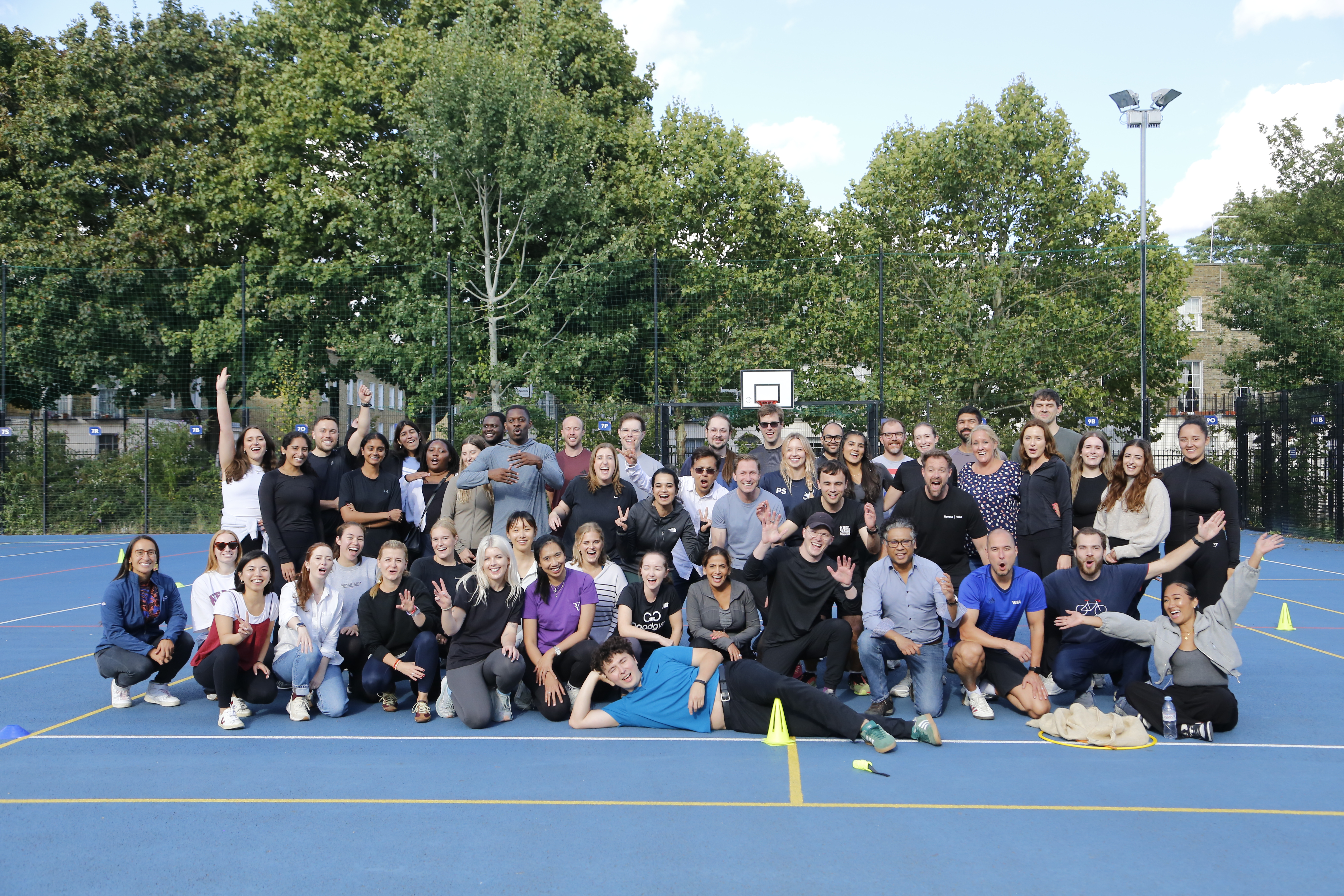 Large group of colleagues posing on an outdoor court at a Sportas company sports day in London
